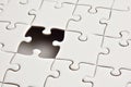 Incomplete white jigsaw puzzle with a single missing piece revealing a dark void Royalty Free Stock Photo