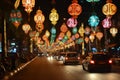 This photograph showcases a lively street adorned with numerous vibrant lights, casting a mesmerizing glow and illuminating the