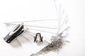 Photograph of some fan-shaped sheets of paper, a stapler, a staple extractor and some paper clips on a white background.The photo