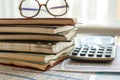A photograph of a stack of books sitting next to a calculator and a pair of glasses, Ledger books stacked up with a calculator and Royalty Free Stock Photo