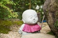 Photograph of a statue of a small angry Buddha with a purple dress