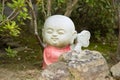 Photograph of a statue of a small angry Buddha with a red dress