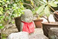 Photograph of a statue of a small happy Buddha with a red dress