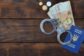 A photograph of a Ukrainian foreign passport, a certain amount of Ukrainian money and police handcuffs. Concept of illegal earnin