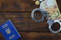 A photograph of a Ukrainian foreign passport, a certain amount of Ukrainian money and police handcuffs. Concept of illegal earnin