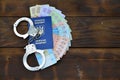 A photograph of a Ukrainian foreign passport, a certain amount of Ukrainian money and police handcuffs. Concept of illegal earnin