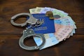 A photograph of a Ukrainian foreign passport, a certain amount of Ukrainian money and police handcuffs. The concept of arresting