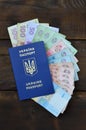 A photograph of a Ukrainian passport and a certain amount of Ukrainian money on a wooden surface. The concept of making money for Royalty Free Stock Photo