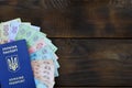 A photograph of a Ukrainian passport and a certain amount of Ukrainian money on a wooden surface. The concept of making money for Royalty Free Stock Photo