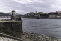 View of the Chain Bridge in the afternoon with the Buda Castle with two cyclists resting on the bank of the Danube, Budapest