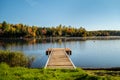 Fall colors reflecting on lake - Landscape scenery - Blue skies, water ripples, Dock on water.