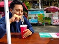 Photograph of a young man chilling and drinking fresh cold red beverage at park Royalty Free Stock Photo