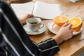 Photographed over the shoulder of a woman, sits at a healthy breakfast with coffee and two orange halves and a fashion magazine Royalty Free Stock Photo