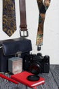 Photographer accessories. Camera and flash. Near tie, belt, suspenders, notebook and pen. On brushed pine boards