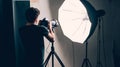 Photographer adjusting camera settings while working with professional studio lighting equipment, highlighting the technical Royalty Free Stock Photo