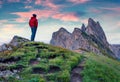 Photographer admires the fantastic sunset with Furchetta peak on background. Picturesque summer scene of Funes Valley. Great