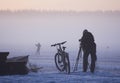 Photographer with a bicycle and winter equipment photographing a