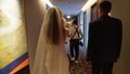 The photographer with the bride and groom are walking along the corridor