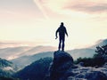 Photographer with camera in hands on top of mountain. Hiker climbed on peak of rock above foggy valley