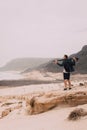 Photographer with camera looking for motive of unique landscape. Sand dunes and volcanic cliffs on the Atlantic