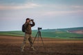 Wildlife photographer looking for animals by binoculars in nature