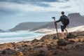 Photographer with camera on tripod in desert admitting unique landscape of sand dunes volcanic cliffs on the Atlantic