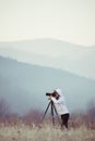 photographer with camera and tripod outdoor taking landscape picture Royalty Free Stock Photo