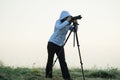 photographer with camera and tripod outdoor taking landscape picture Royalty Free Stock Photo