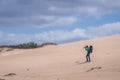 Photographer carrying young baby in backpack while shooting on the sandy dunes