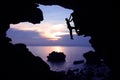 Photographer climbing rock in the cave near the beach with kayaking. Royalty Free Stock Photo