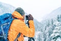 Photographer dressed orange softshell jacket with backpack making a landscape shoot using a digital camera and tripod while he Royalty Free Stock Photo