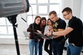 Photographer explaining about the shot to his team in the studio and looking on laptop. Talking to his assistants holding a camera