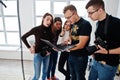 Photographer explaining about the shot to his team in the studio and looking on laptop. Talking to his assistants holding a camera