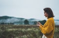 Photographer girl hold in hands mobile phone typing message on smartphone on background autumn froggy mountain, internet online