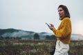 Photographer girl hold in hands mobile typing message on smartphone on background landscape autumn froggy mountain, tourist shoot