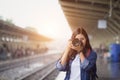 Photographer girl smile holding digital camera. Young Asian woman traveler with camera taking pictures on subway train platform. Royalty Free Stock Photo