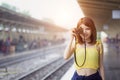 Photographer girl smile holding digital camera. Young Asian woman traveler with camera taking pictures on subway train platform. Royalty Free Stock Photo