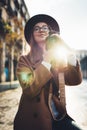 Photographer in glasses with retro photo camera. Tourist portrait girl in hat travels in Barcelona holiday. Sunlight flare street Royalty Free Stock Photo