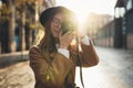 Photographer in glasses with retro photo camera. Tourist portrait. Girl in hat travels in Barcelona holiday. Sunlight flare street Royalty Free Stock Photo