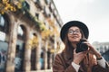 Photographer in glasses take photo on retro camera. Tourist portrait. Girl in hat travels in Barcelona holiday. Street in europe