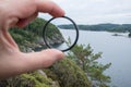 Photographer hand puts a polarization filter on the camera, against the backdrop of a beautiful landscape of the sea and Royalty Free Stock Photo