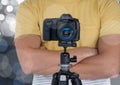 photographer hands folded with camera with tripod in front. Silver bokeh behind Royalty Free Stock Photo