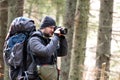 Photographer with hiking backpack taking pictures of nature with digital photo camera Royalty Free Stock Photo