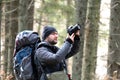 Photographer with hiking backpack taking pictures of nature with digital photo camera Royalty Free Stock Photo