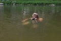 photographer holding camera swimming quietly by river with just head above water trying to catch some interesting shots