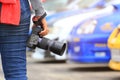 Photographer holding DSLR camera in his hands with standing at the car parking lot Royalty Free Stock Photo