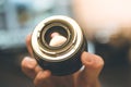 Photographer is holding a photography lens in his hand, laptop in the blurry background Royalty Free Stock Photo