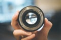 Photographer is holding a photography lens in his hand, laptop in the blurry background Royalty Free Stock Photo