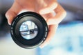 Photographer is holding a photography lens in his hand, laptop in the blurry background Royalty Free Stock Photo