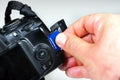 Photographer inserting or removing a blue memory card into the slot in the camera Royalty Free Stock Photo